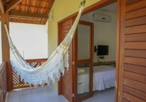 a hammock in a room with a bed at Zion Suítes in Jericoacoara