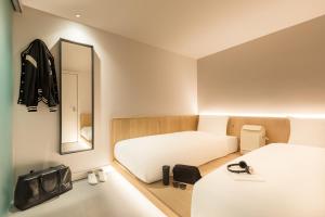 a small room with two beds and a mirror at Zedwell Underground Hotel Tottenham Court Rd in London