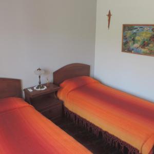 een slaapkamer met 2 bedden met oranje lakens en een tafel bij Casa en Alquiler Temporario in Olavarría