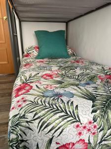 a bed with a floral comforter and a green pillow at Alojamiento entero. Piso en el centro de El Vendrell. in El Vendrell