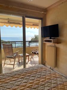 a bedroom with a bed and a balcony with a television at Résidence CENTER BAY - Juan les Pins in Juan-les-Pins
