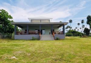 uma pequena casa com um grande campo relvado em frente em La Maison Hebridaise em Luganville