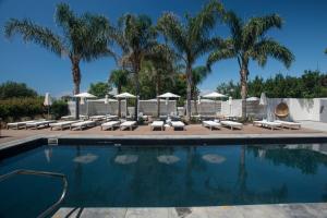 - une piscine avec des chaises longues et des palmiers dans l'établissement La Suite Boutique Hotel, à Procida