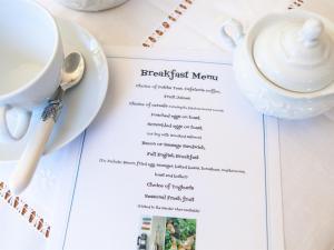 a table with a cup of coffee and a menu at Birch House Bed & Breakfast in Weymouth