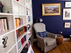 een blauwe kamer met een stoel en boekenplanken bij Birch House Bed & Breakfast in Weymouth