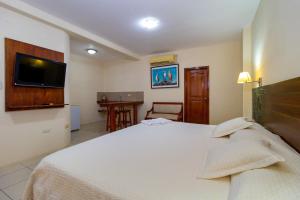 a bedroom with a bed and a tv on the wall at Hotel Villa Laguna in Puerto Ayora