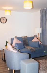 a blue couch in a living room with a clock at Luxurious MK Apartment-Campbell Park in Milton Keynes