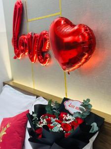 a bed with a bouquet of roses and heart balloons at Khách Sạn K’My in Ấp Phú Thọ