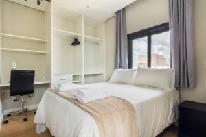 1 dormitorio con 1 cama blanca, ventana y escritorio en BHomy Paulista Localização excelente MR174, en São Paulo