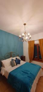 ein Schlafzimmer mit einem Bett mit einer blauen Decke und einem Kronleuchter in der Unterkunft Argonauti Rooms Retreat in Pistoia