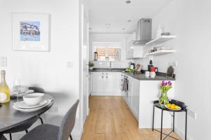 a white kitchen with a table and a dining room at Osprey 3, The Cove, Brixham in Brixham +10 photos
