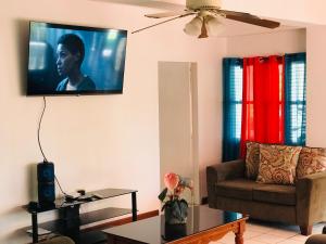 ein Wohnzimmer mit einem Flachbild-TV an der Wand in der Unterkunft HCEAS villa is 5 min fr. airport & to the beaches in Bon Accord