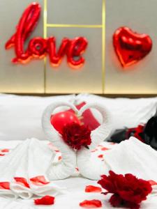 uma cama com dois corações e rosas e um sinal de amor em Khách Sạn K’My em Ấp Phú Thọ