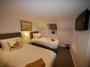 a hotel room with two beds and a flat screen tv at The Gather Inn in Brighton & Hove