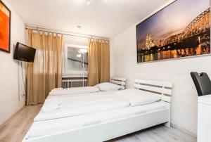 two beds in a white room with a tv at Easy Apartments Work and Stay Cologne in Cologne