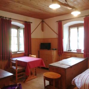 Cette chambre comprend une table, un lit et des rideaux rouges. dans l'établissement Al Piz Monolocale, à Colle Santa Lucia