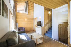 a living room with a couch and a tv at Residence Refuge du Golf - maeva Home in Flaine