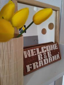 een welkomstbord en een vaas met bloemen bij B&B Fradama' Holiday in Dorgali