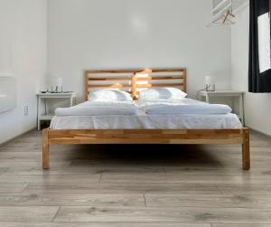 1 dormitorio con cama de madera con sábanas y almohadas blancas en Pixel Guesthouse, en Tîrgu Secuiesc