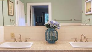 a bathroom with two sinks and a vase of flowers at 160 Long Pond Drive Harwich Cape Cod - Old Camp in Harwich +41 photos