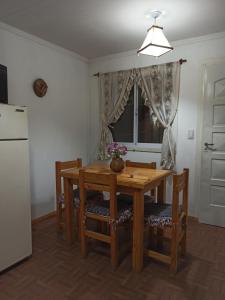 cocina con mesa de madera, sillas y nevera en Casita de Montaña en Cosquín