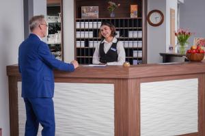 a man and a woman shaking hands at a counter at Best Western Comfort Business Hotel Düsseldorf-Neuss in Neuss