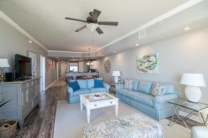 een woonkamer met blauwe banken en een plafondventilator bij Sienna 1103 in Gulfport