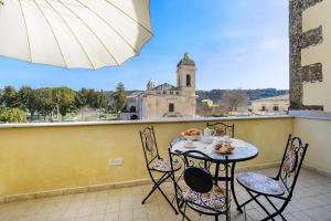 a table and chairs on a balcony with a view of a building at HyblaLifeRooms in Ragusa