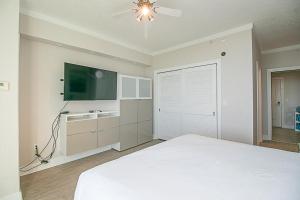 1 dormitorio con 1 cama blanca y TV de pantalla plana en Ocean Club 1206 en Biloxi