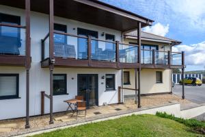 an apartment building with a balcony and a table at White Lodge Apartments in Mawgan Porth