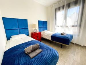Un dormitorio con dos camas y una mesita de noche roja. en Sunny Luxury Apartment with two great sunny - level terraces, two swimming pools, in a new complex Pueblo Majorero, close to Fuerteventura Golf Club, next to the beach , Atlantico Shopping Mall and casino in Caleta de Fuste, en Caleta de Fuste 65 fotos más