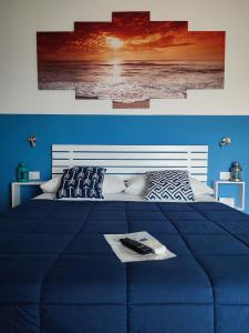 a blue bedroom with a large blue bed with two paintings at B&B Fradama' Holiday in Dorgali