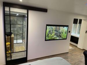 a room with a white wall with a television on it at Nuit de la sagesse "jacuzzi terrasse et parking privé" in Rouen