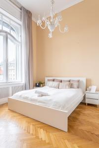 Habitación blanca con cama grande y lámpara de araña. en Matilda Luxury Suite Apartment en Budapest