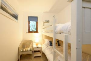 een kleine kamer met een stapelbed en een stoel bij White Lodge Apartments in Mawgan Porth