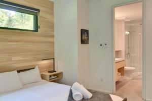 1 dormitorio con cama blanca y baño en 1 Impasse du Cardinal - Lac Superior Chalet w Spa Sauna & Games Room en Mont-Tremblant