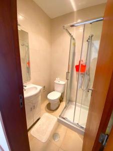 a bathroom with a toilet and a glass shower at Mindelo Beach House in Vila Chã