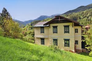 a yellow house on a hill with mountains in the background at Villa Anima in Prein