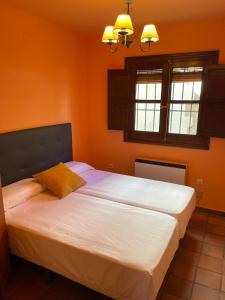1 dormitorio con 2 camas y paredes de color naranja en Apartamentos Hoz del Huécar, en Cuenca