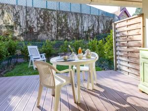 une table et des chaises blanches sur une terrasse en bois dans l'établissement Apartment Le Parc de La Ronceray-5 by Interhome, à Dinard