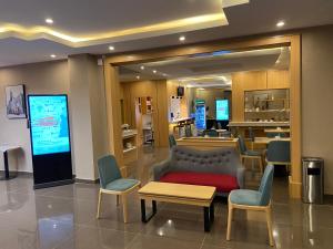 a lobby with a waiting area with a couch and chairs at Ivy Hotel Emerald in Ikeja