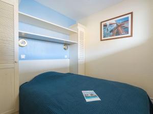 sypialnia z niebieskim łóżkiem i zdjęciem na ścianie w obiekcie Apartment Bleu Marine-10 by Interhome w mieście Lacanau-Océan