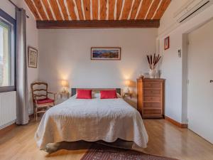 een slaapkamer met een bed met rode kussens en een houten plafond bij Apartment L'Aquilon by Interhome in Noves