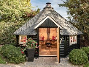 a black play house with a thatch roof at Holiday Home Het Landhuis by Interhome in Losser