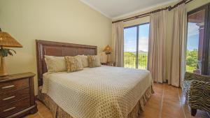 1 dormitorio con cama y ventana grande en Bougainvillea 1101 Luxury Apartment - Reserva Conchal, en Brasilito