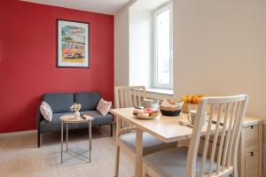 a dining room with a table and chairs and a red wall at La Source aux Cépages in Santenay