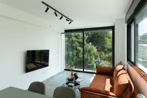 a living room with a couch and a large window at Zeev Jabotinsky Residence - With Mamad in Tel Aviv