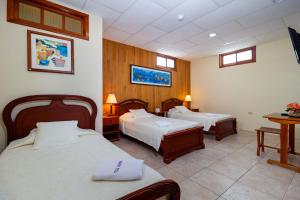 a hotel room with two beds and a table at Hotel Villa Laguna in Puerto Ayora