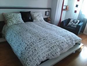 a bedroom with a bed with a white comforter and a chair at Buenos Aires apartamento in Guadix