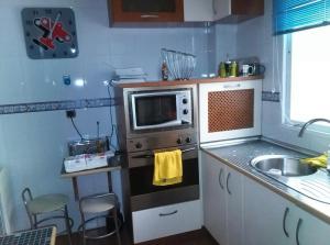a small kitchen with a microwave and a sink at Buenos Aires apartamento in Guadix